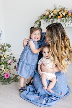 Mother cuddling her young daughter in a floral studio setting