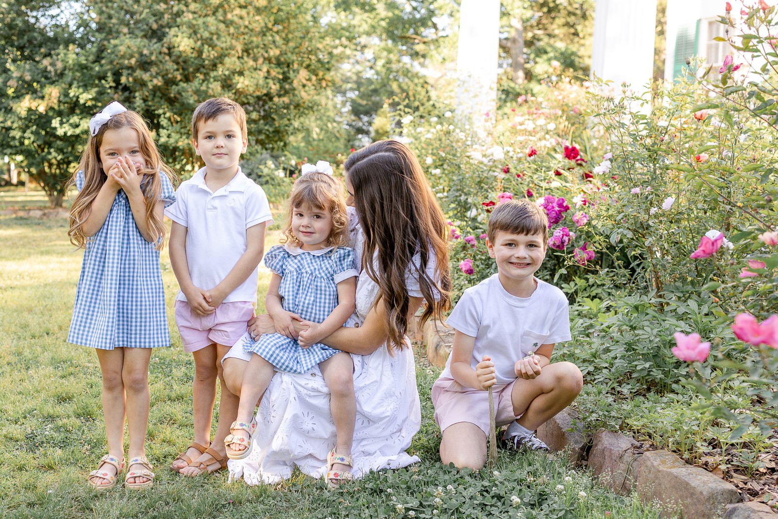A mother and four children together in a sunlit flower garden