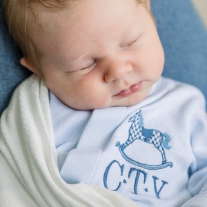 Newborn sleeping peacefully in a soft blue wrap