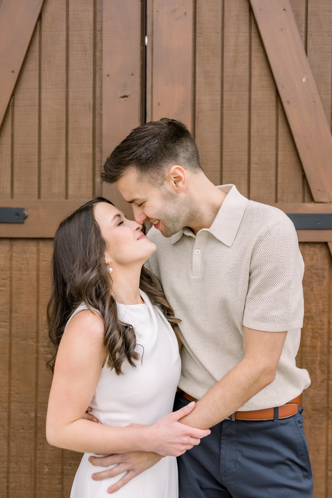 Engaged couple sharing a quiet moment beside rustic wooden doors