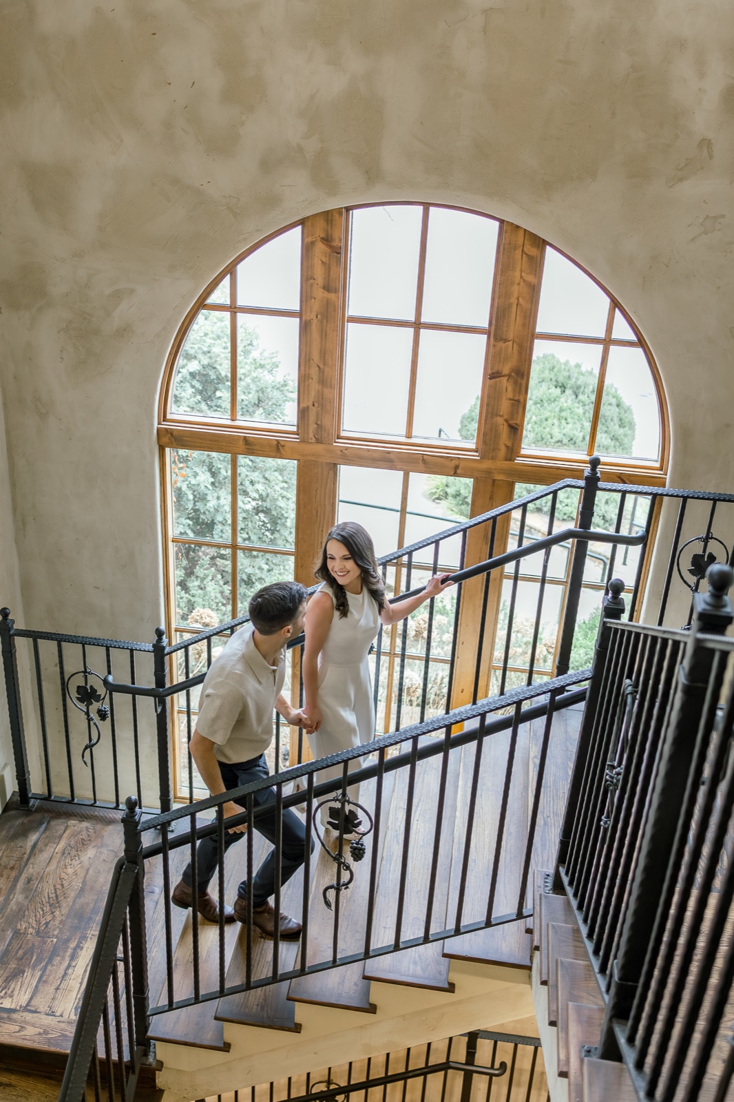Engaged couple walking through a grand staircase at the vineyard