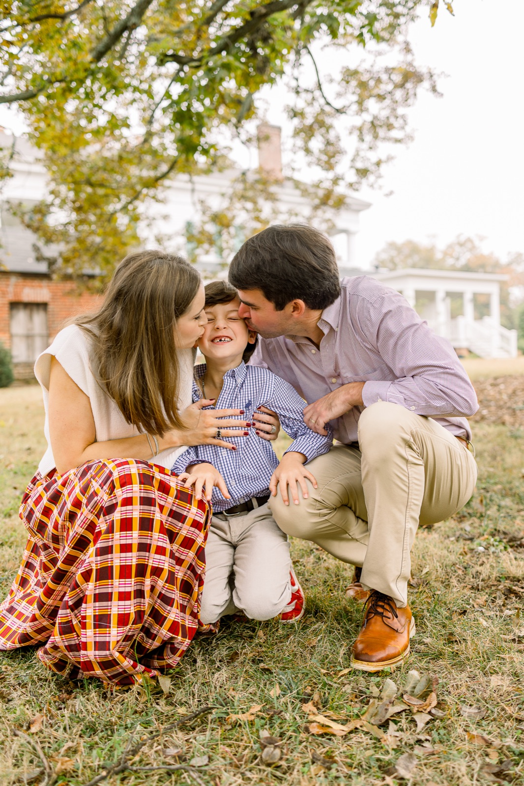 Parents kissing their son during an autumn family session