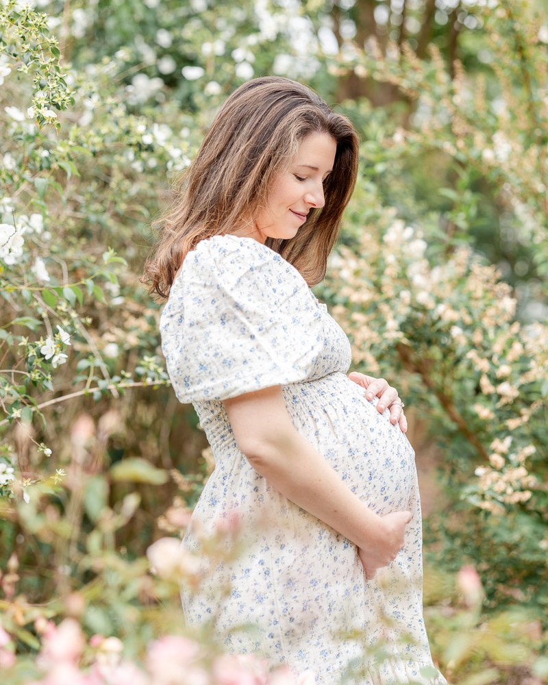 Expectant mother standing outdoors in a light dress