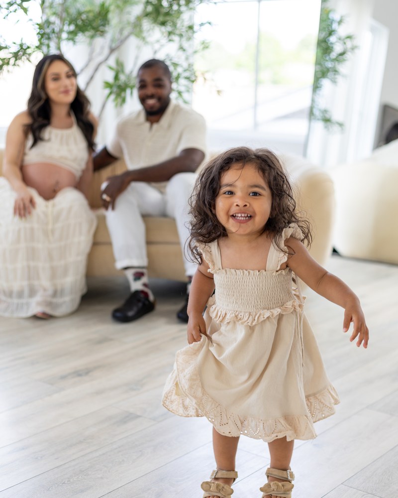Young daughter smiling in front of her expectant parents