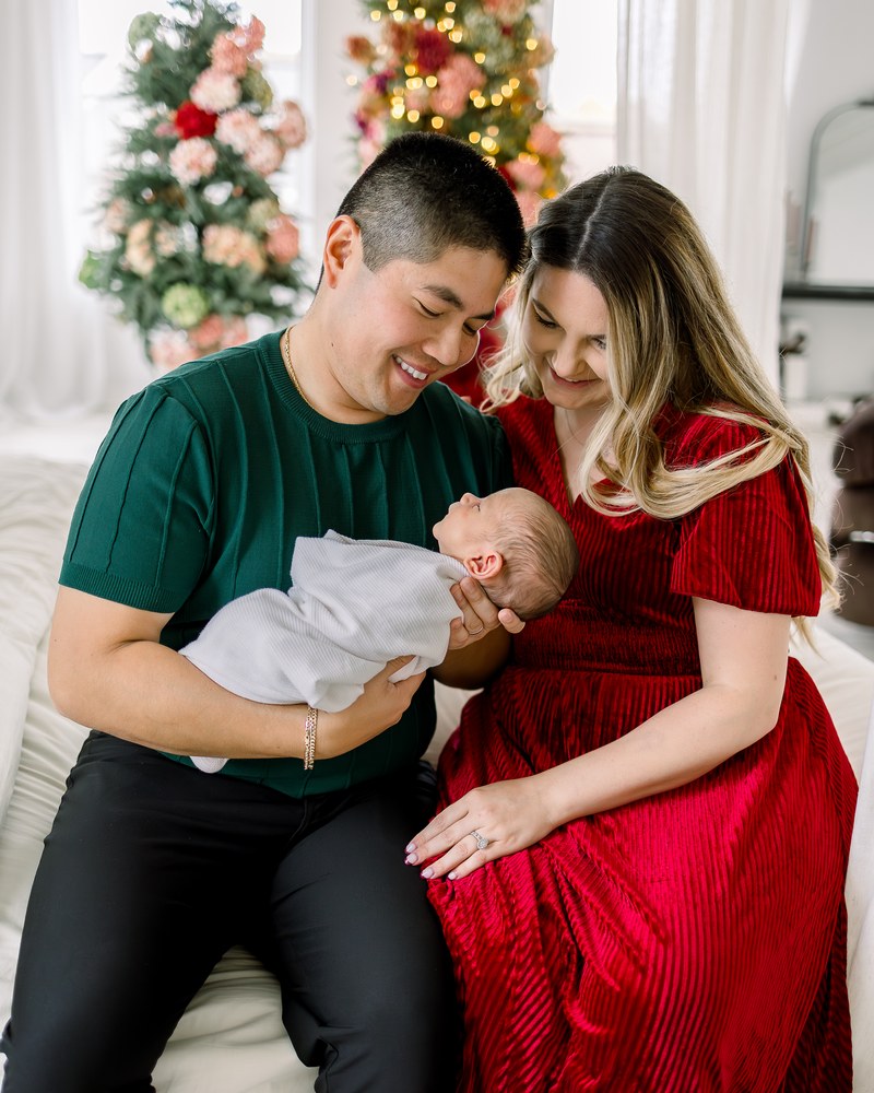 Parents holding their newborn together in a bright holiday studio