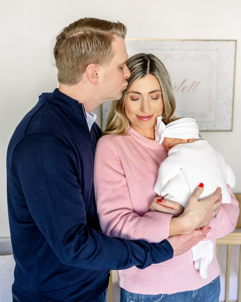 Parents holding their newborn together in her nursery