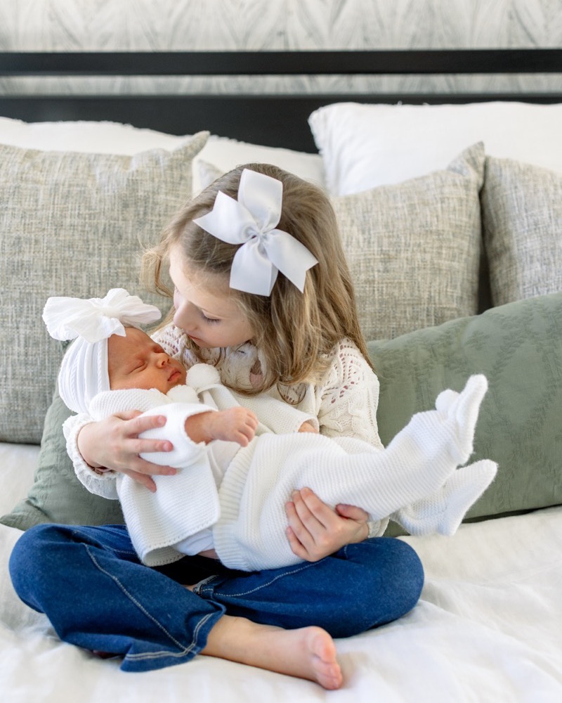Big sister gently holding her newborn sibling
