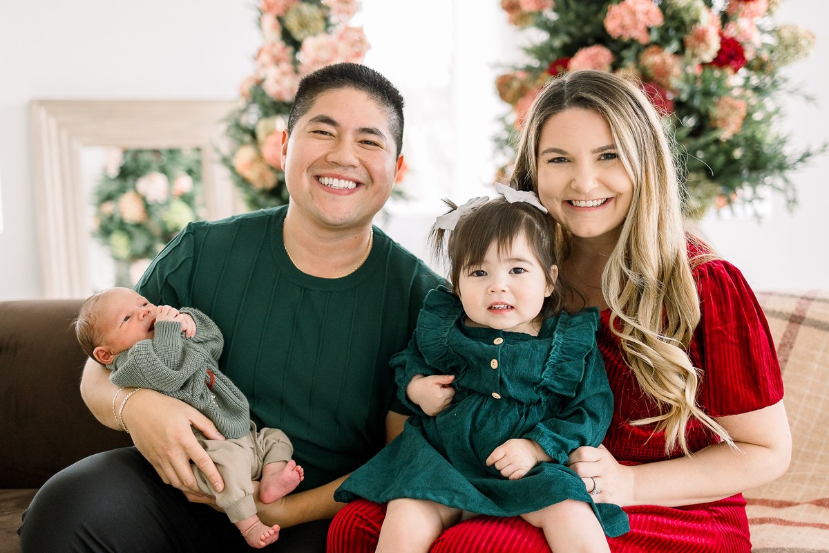 Family of four gathered with their newborn in a holiday studio