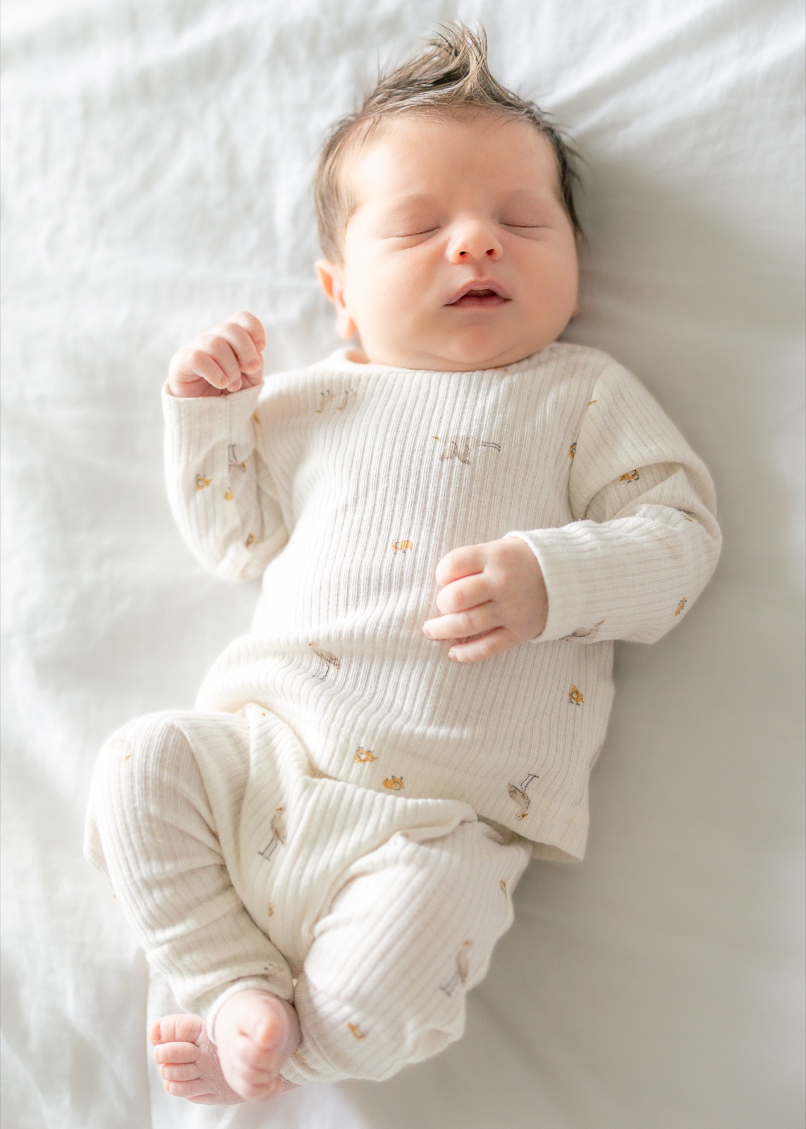 Newborn sleeping peacefully on a white blanket