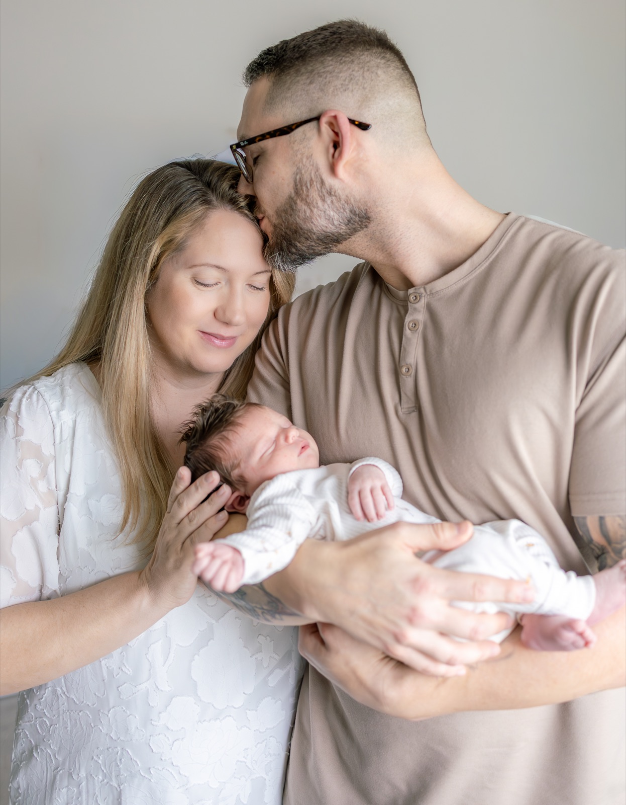Newborn held by his parents in their home
